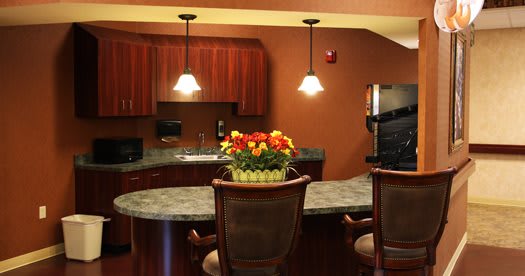 A cozy kitchen with pendant lighting, a granite countertop, and vibrant flowers as a centerpiece.