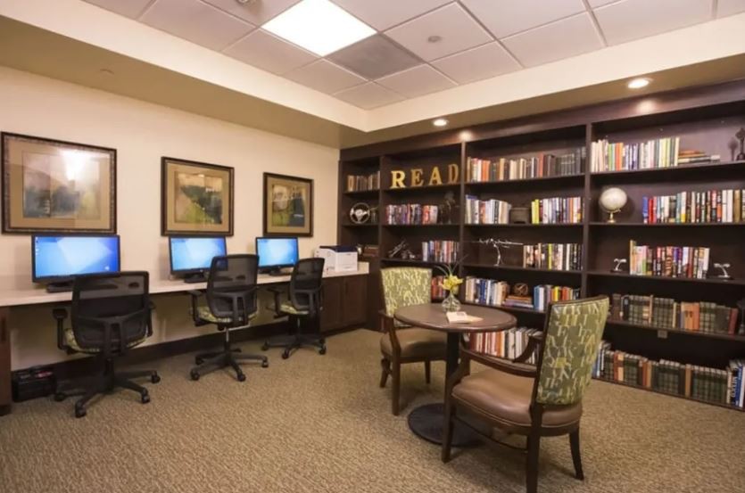A cozy library corner featuring computer stations, bookshelves, and a reading area with comfortable chairs.