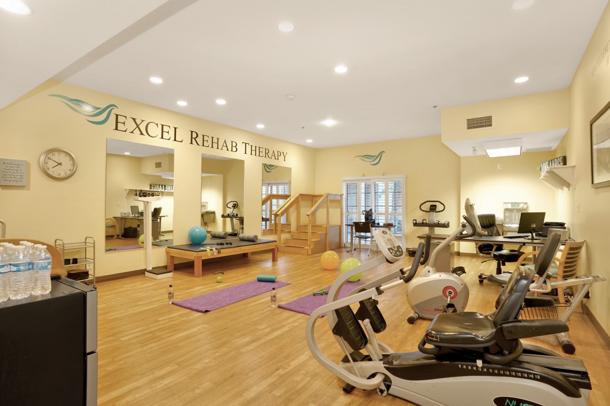 Rehabilitation therapy room equipped with various exercise machines and mats.