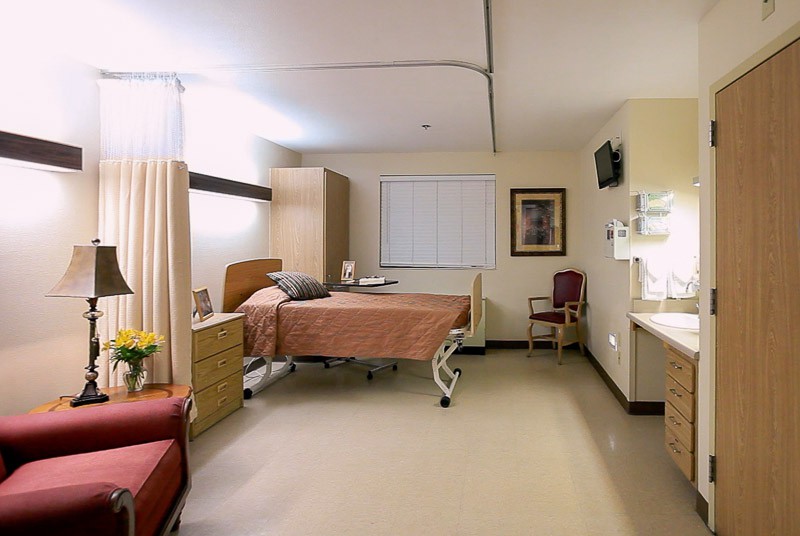 A clean and well-lit hospital room equipped with a bed and medical furniture.