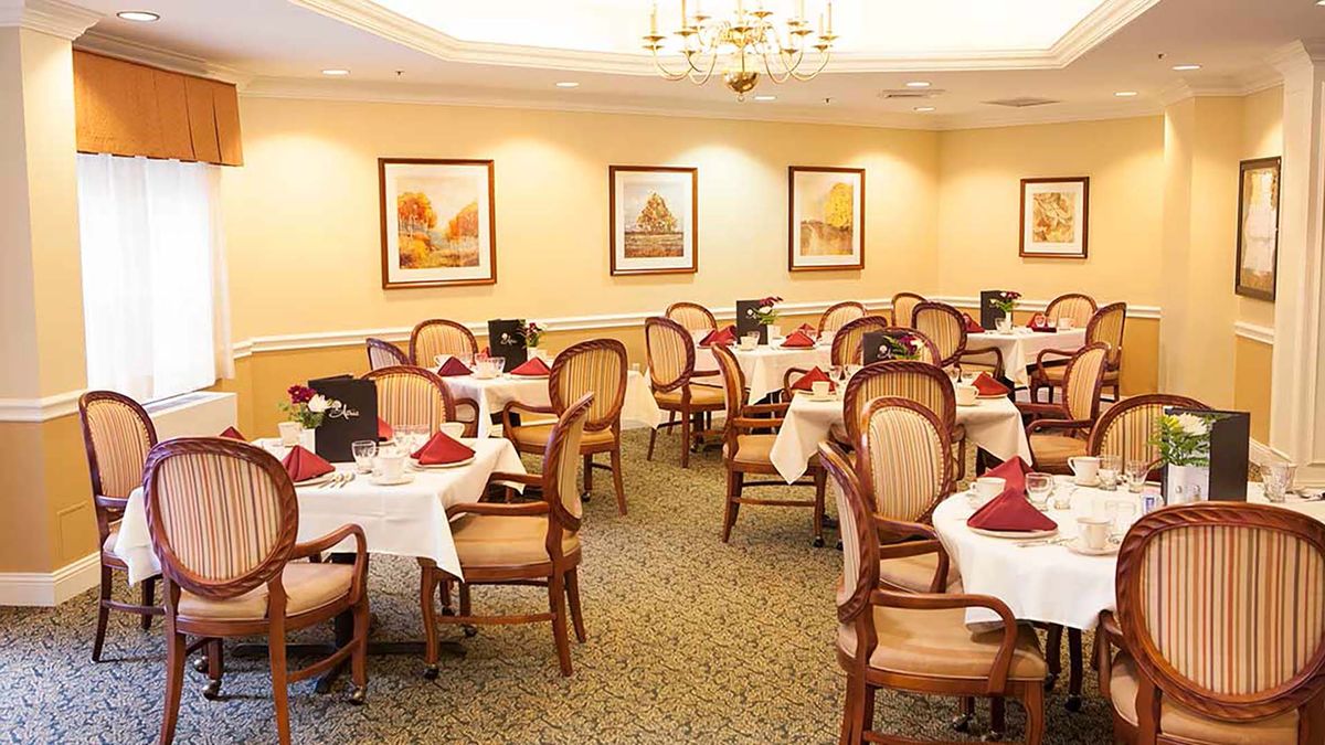 An elegant dining room with neatly arranged tables and chairs, adorned with artwork on the walls.