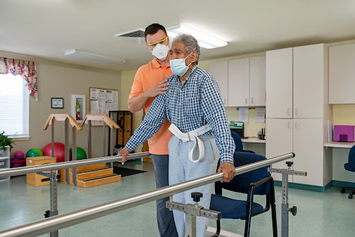 A healthcare professional assists an elderly patient during physical therapy, focusing on rehabilitation in a supportive environment.