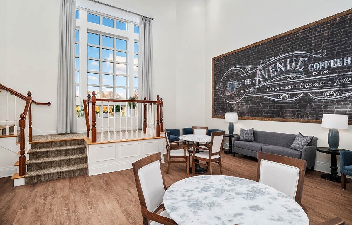 A bright living space with large windows, comfortable seating, and decorative chalkboard art.