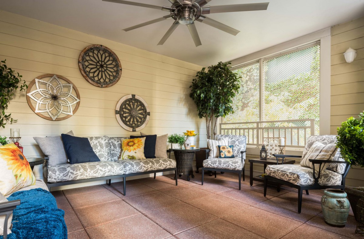 A cozy sunroom featuring stylish furniture, wall art, and large windows with natural lighting.