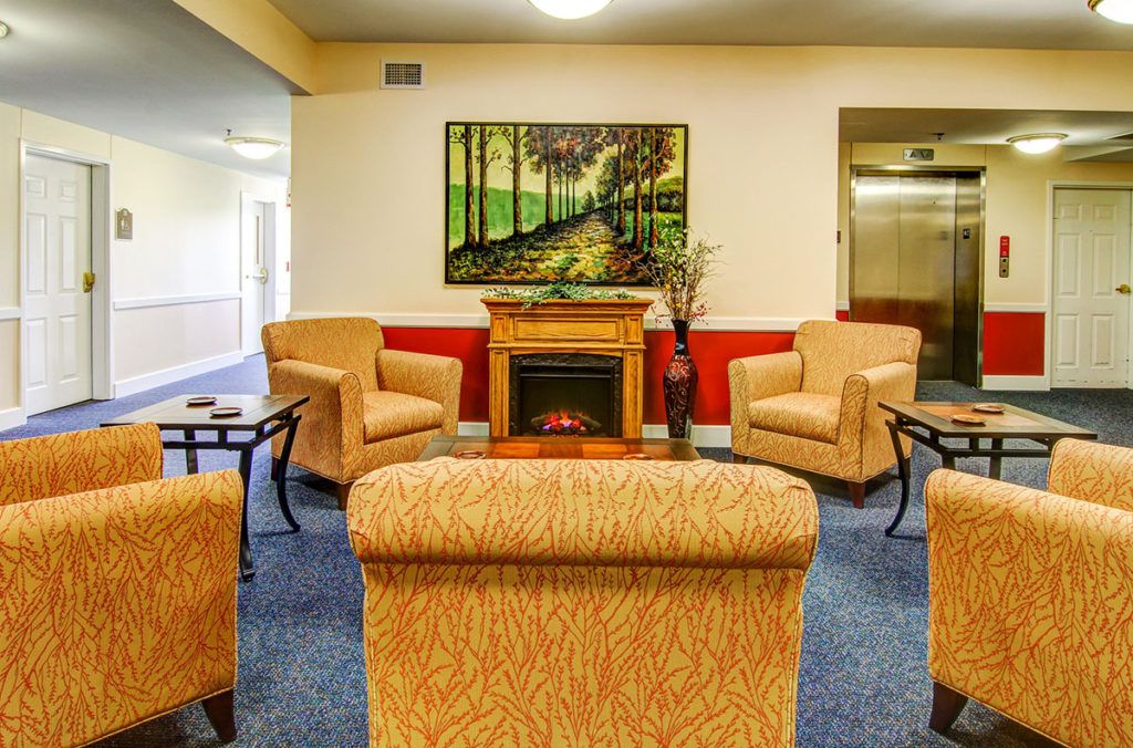 A cozy living room with comfortable seating and a fireplace, adorned with artwork on the wall.
