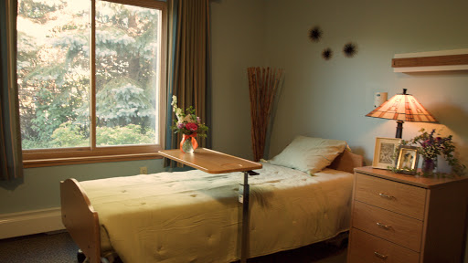 A serene and inviting bedroom with natural light streaming in through the window, featuring a neatly made bed and a decorative flower arrangement.