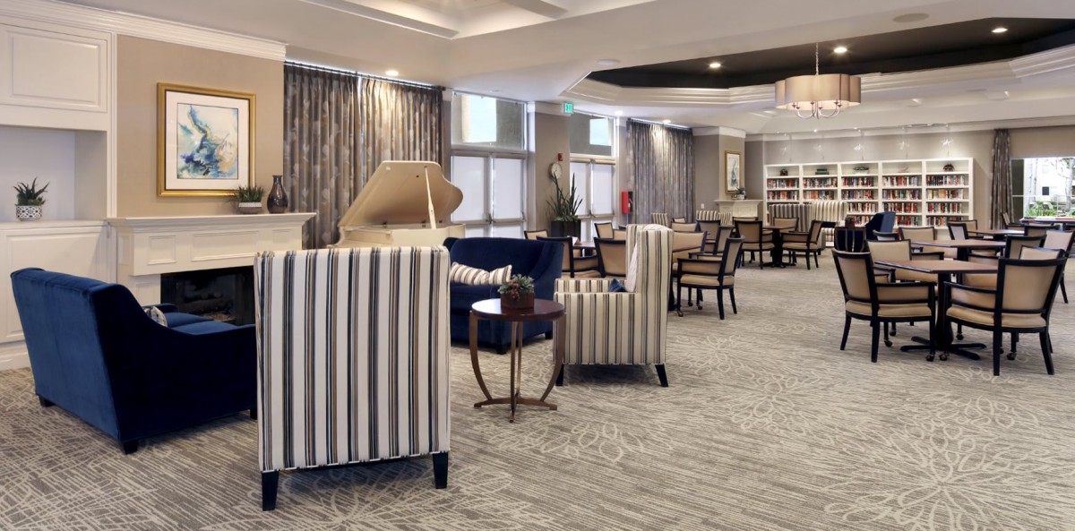 A spacious and elegantly decorated lobby with striped chairs, tables, and a piano.