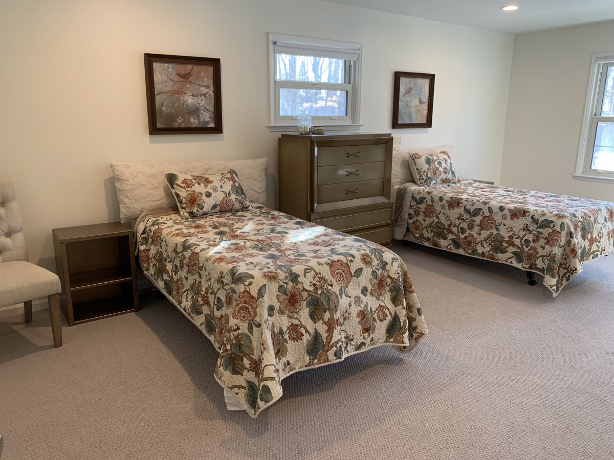 A cozy bedroom featuring twin beds with floral bedding and vintage furniture.