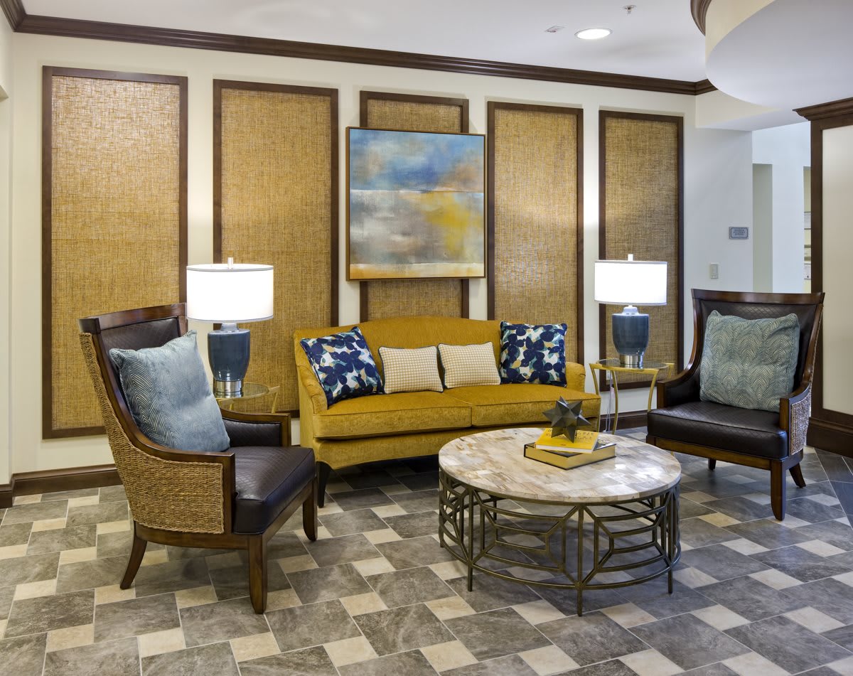 A stylishly furnished living room with a modern sofa, chairs, coffee table, and decorative lamps.