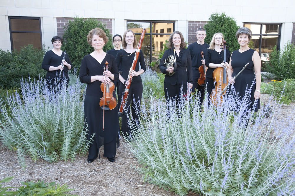 A group of musicians posing outdoors with their string instruments.