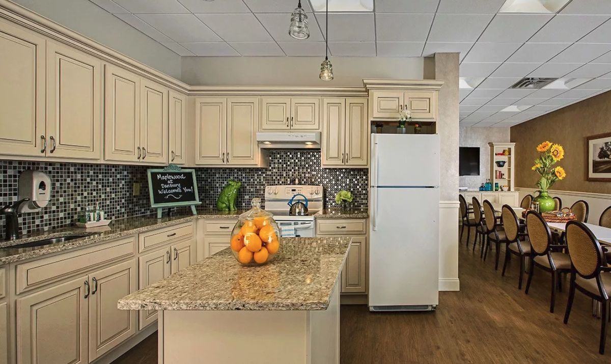 A modern kitchen with cream cabinets, a granite island countertop, and stainless steel appliances.