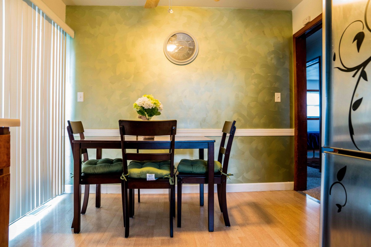 A cozy dining room with a green accent wall and a simple, elegant table setting.