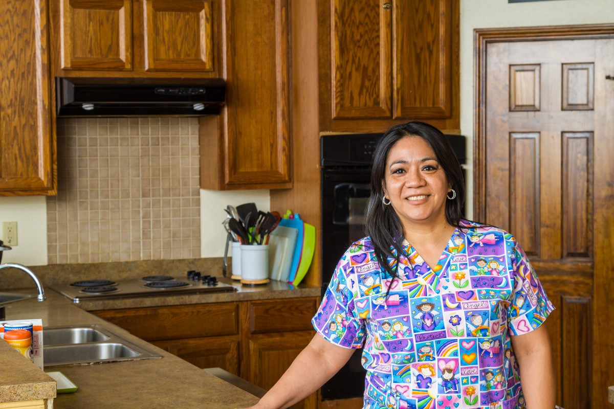 A woman smiling in a kitchen setting.