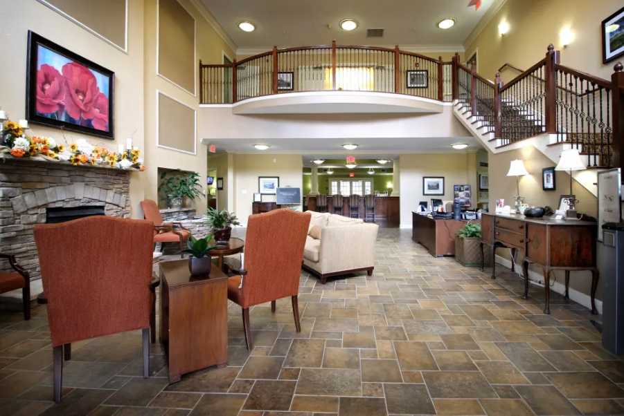 A spacious lobby interior featuring comfortable seating, a reception area, and an elegant staircase.