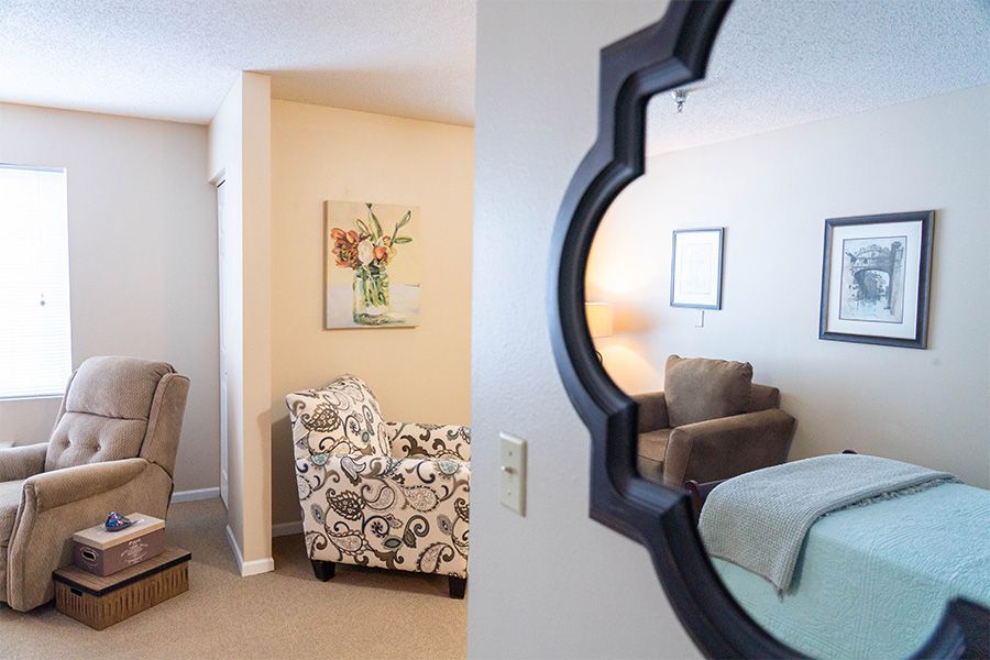 A cozy living room with patterned furniture and artwork, reflected in a decorative wall mirror.