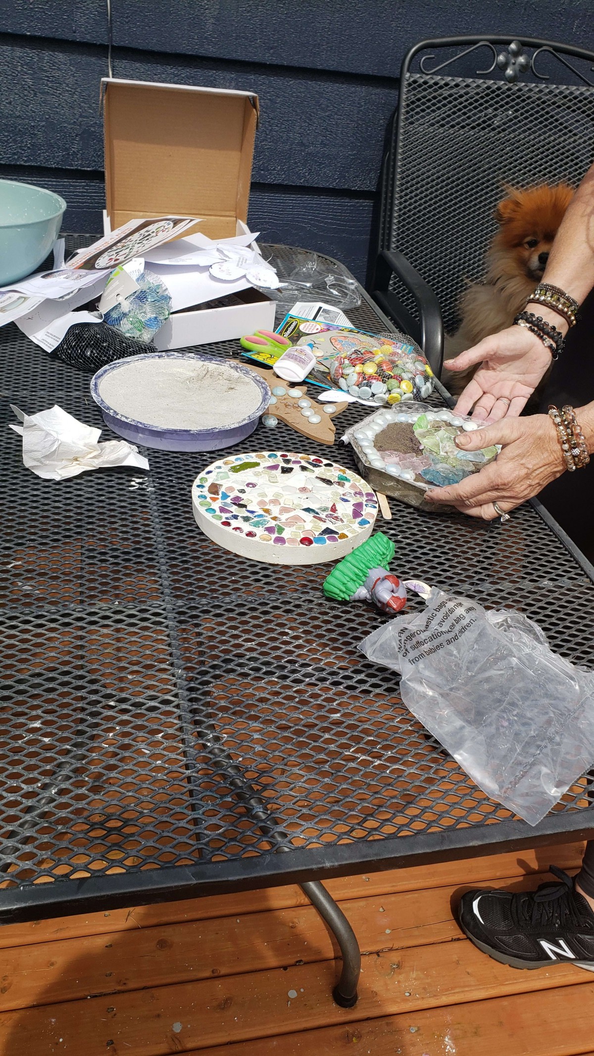 A person working on a mosaic art project with various craft materials on a table.
