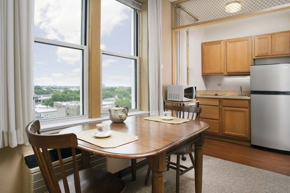 A modern kitchen and dining area with a wooden table, chairs, and large windows offering a scenic view.
