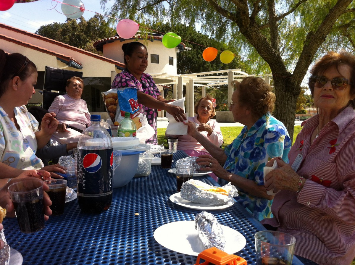 A family gathering outdoors with food, drinks, and festive decorations.