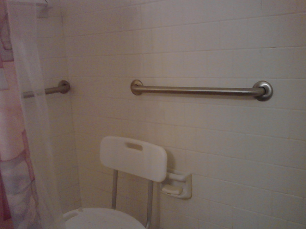 A bathroom with grab bars and a chair, designed for accessibility.