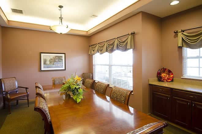 A well-lit dining room featuring a long wooden table and chairs, adorned with floral centerpiece and artwork on the wall.