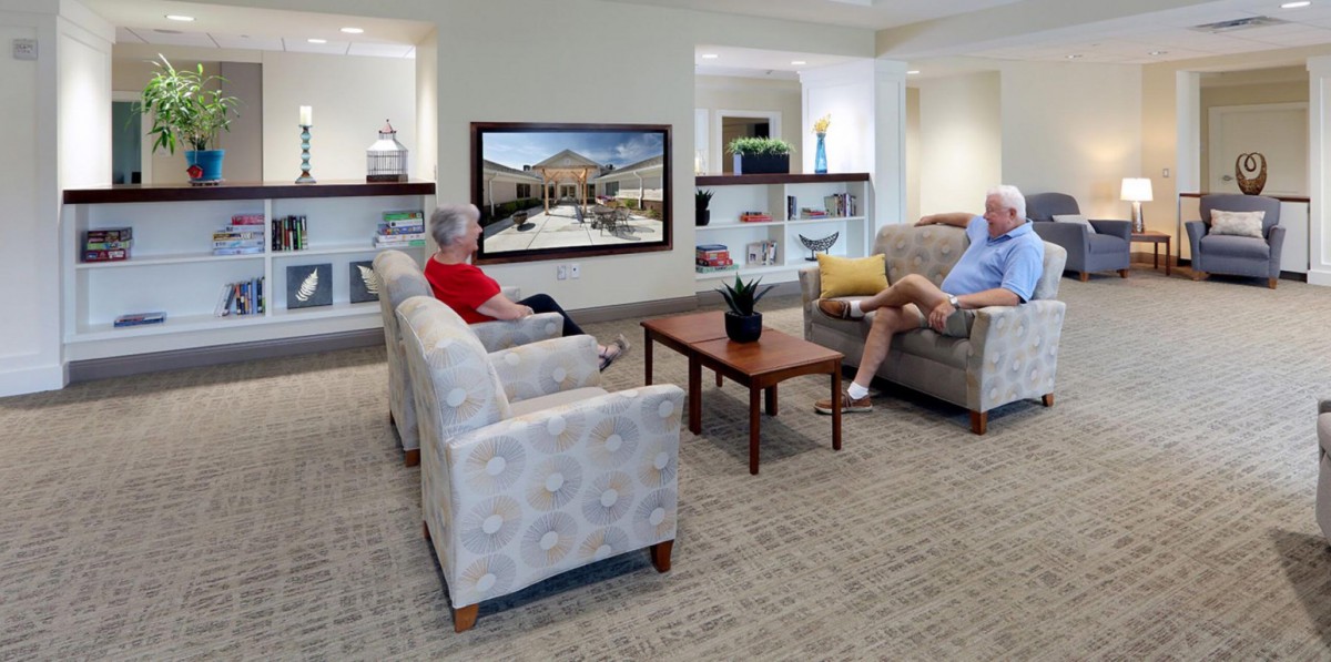 Two people sitting in a cozy living room with modern decor and a large television.