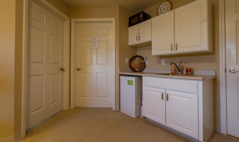 A small kitchen area with white cabinets and a mini fridge.