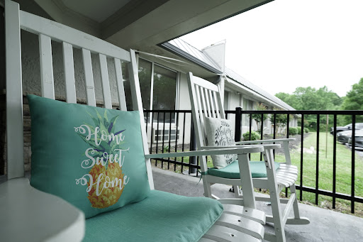 A cozy outdoor space featuring white rocking chairs with soft cushions, perfect for relaxation.