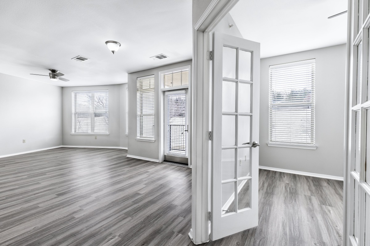 A bright living space with hardwood floors, large windows, and French doors.