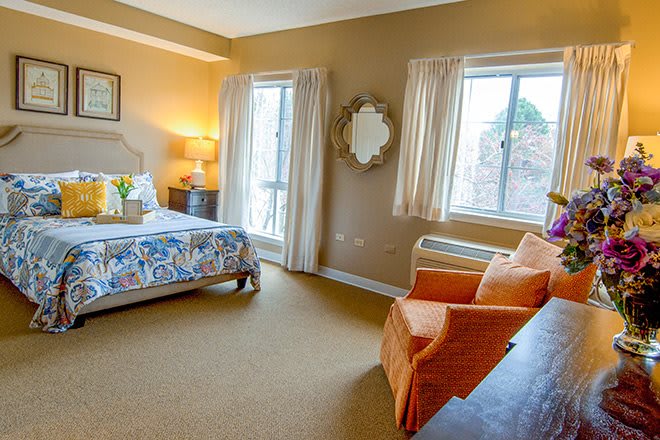 A cozy bedroom interior with a bed, armchair, and decorative elements.