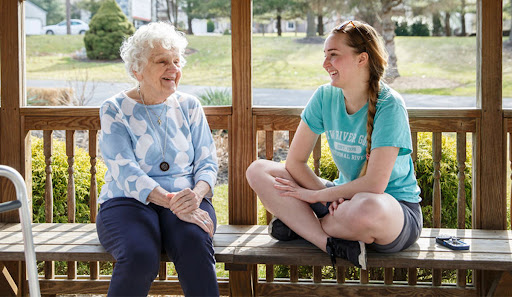 A heartwarming moment between a young woman and an elderly lady enjoying a conversation outdoors.