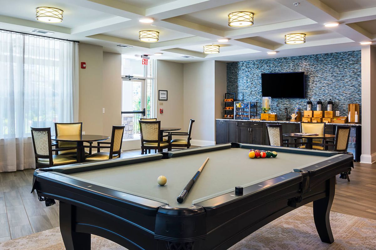 A modern recreation room featuring a pool table, seating area, and television.