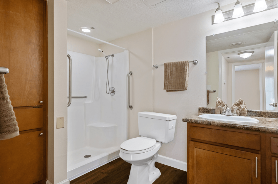 A modern bathroom featuring a shower, toilet, and sink with a mirror.