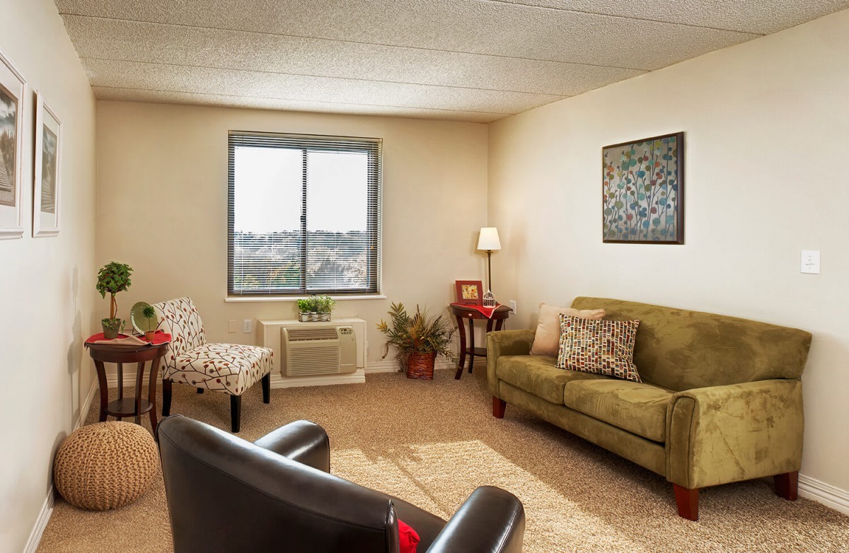 A cozy living room with a sofa, armchairs, and a window providing natural light.