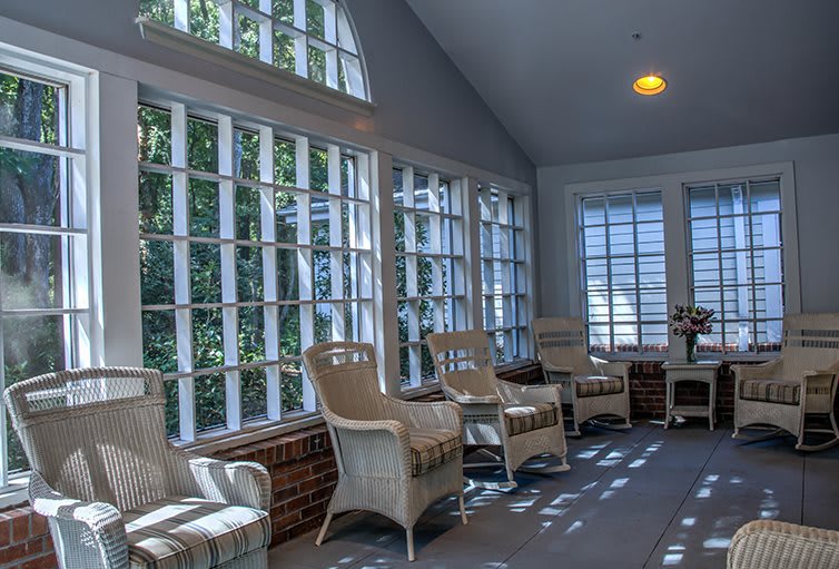 A sunroom filled with wicker furniture and large windows allowing natural light to flood the space.