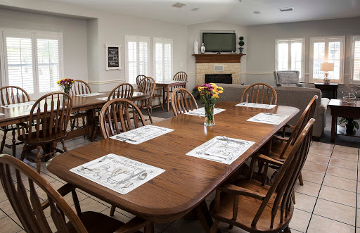 A cozy dining area featuring wooden tables and chairs, adorned with a vase of flowers.