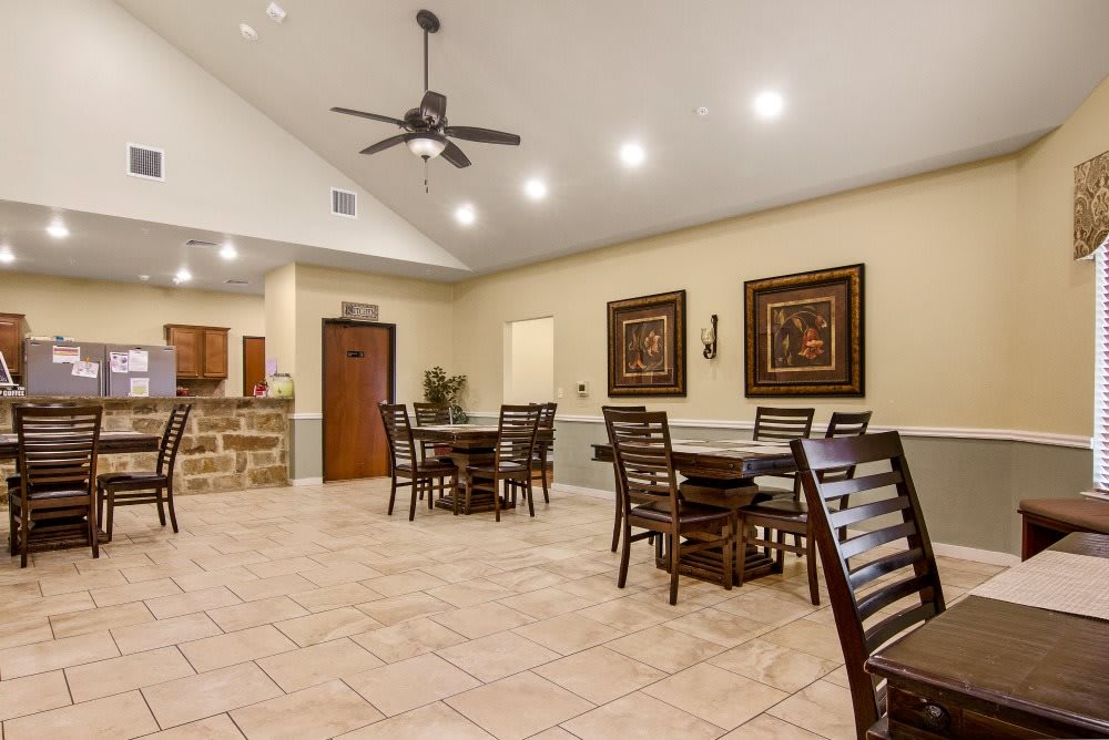 A spacious dining area with tables and chairs, featuring a ceiling fan and artwork on the walls.
