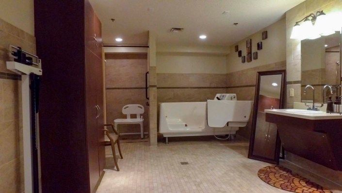 A spacious public restroom with urinals and tile flooring, featuring partitions and indoor lighting.