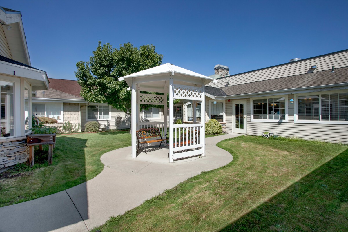 A peaceful courtyard with a gazebo and well-maintained lawn on a sunny day.