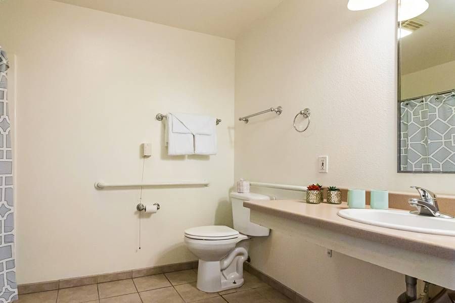 A clean and accessible bathroom with a toilet, sink, and grab bars.