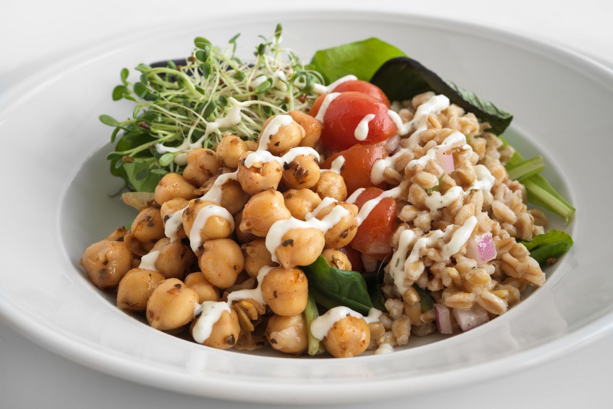 A healthy vegetarian salad with chickpeas, grains, tomatoes, and fresh greens.