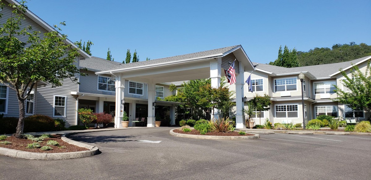 A view of a large building entrance with columns, surrounded by landscaping and flags.