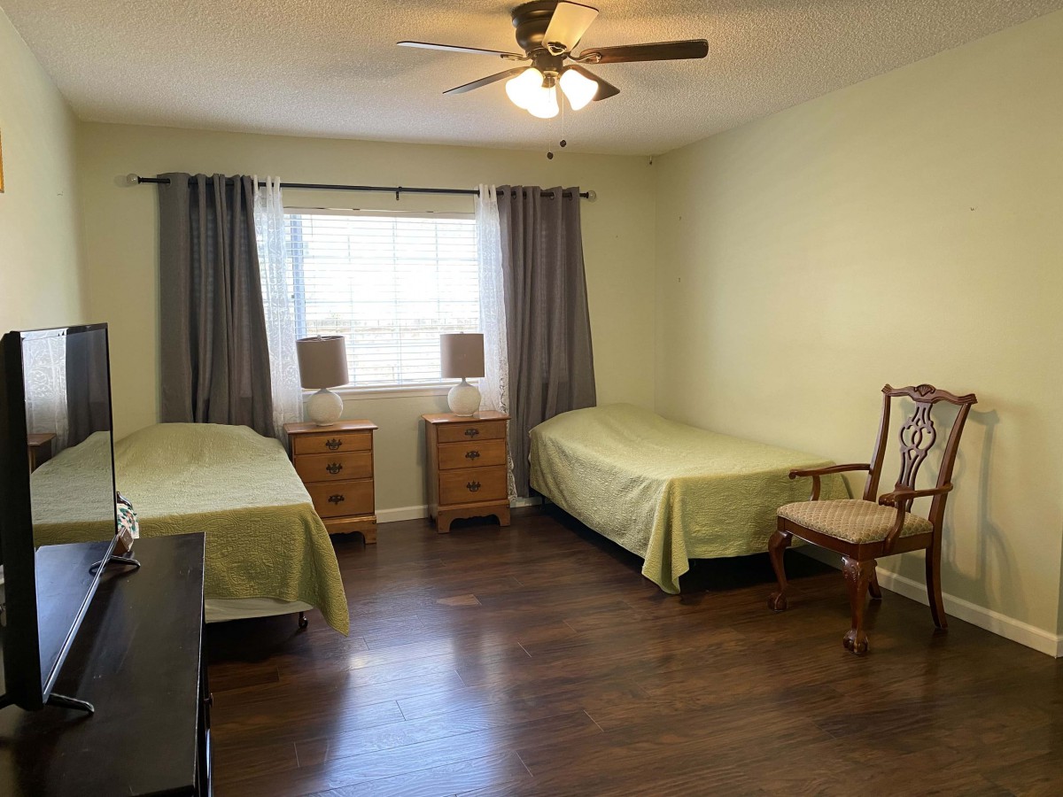 A tidy bedroom with two single beds, nightstands, and a ceiling fan.