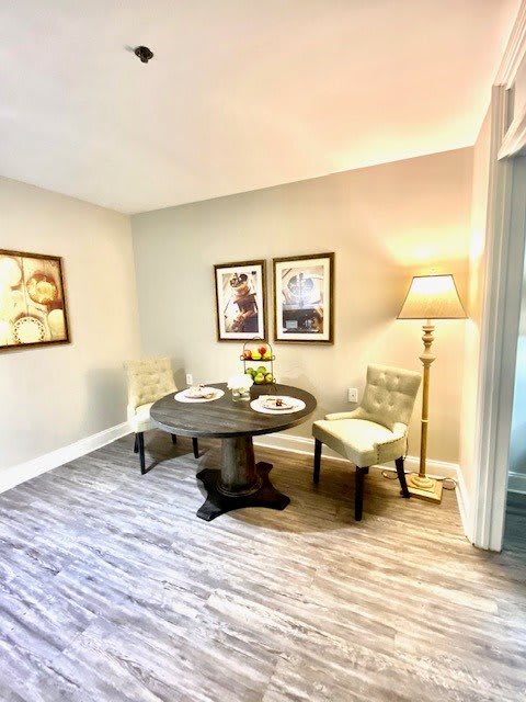 A cozy dining area featuring a round table, two chairs, and warm lighting.