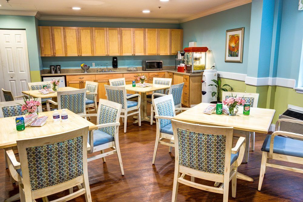 A cozy dining area with wooden tables and chairs, featuring a kitchen space and a popcorn machine.
