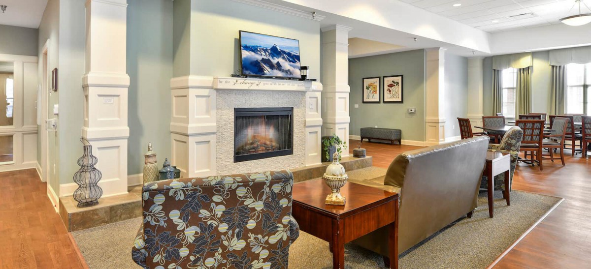 A cozy living room with a fireplace and a television above it.