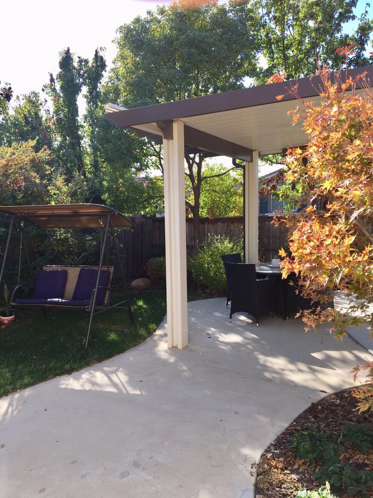 A peaceful backyard with a swing and patio seating surrounded by lush greenery.