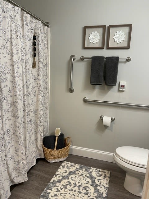 A modern bathroom with grey walls, floral shower curtain, and neatly arranged decorations.