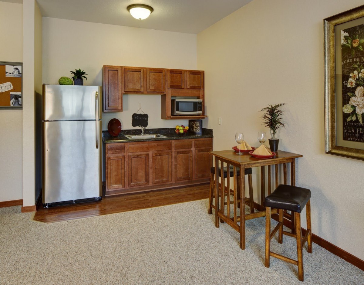 Cozy kitchenette with wooden cabinets and a small dining area.