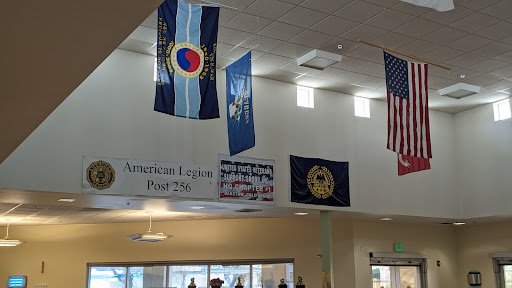 An interior view featuring various flags, including the Colorado state flag and American Legion banner.