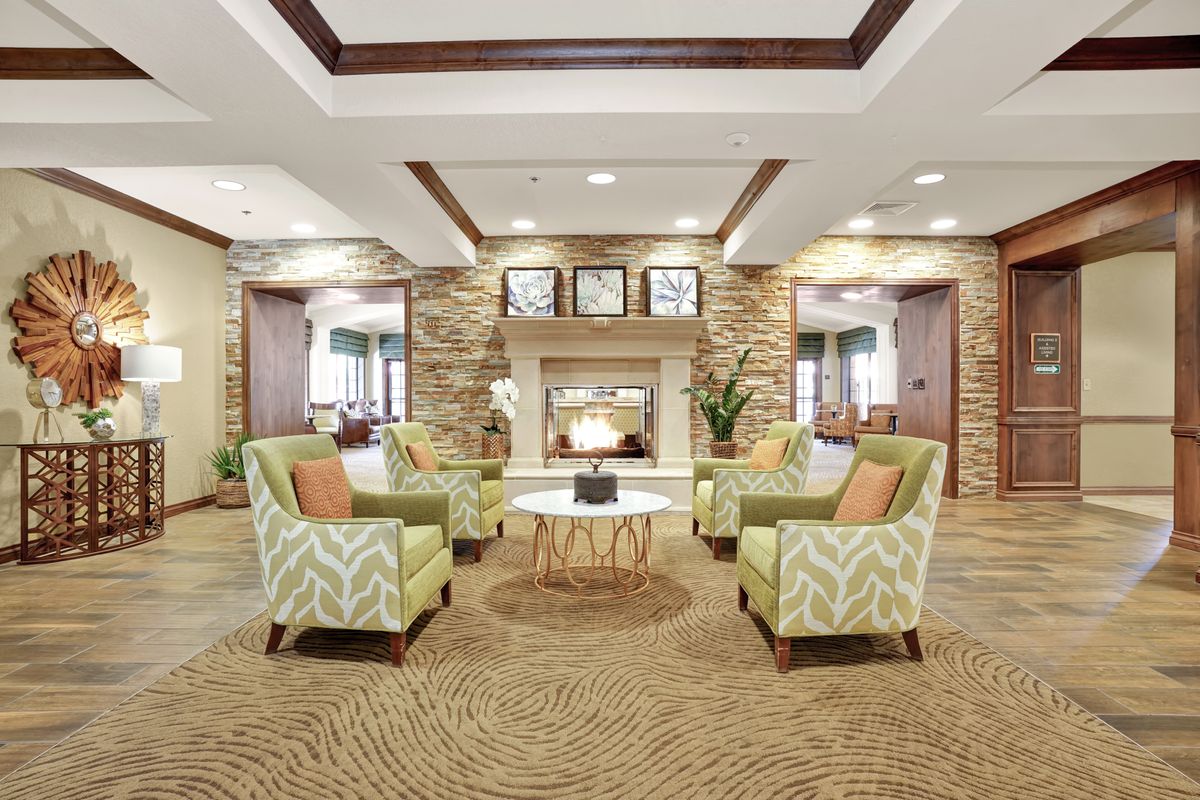 A modern and cozy lobby with a central fireplace, surrounded by comfortable seating and elegant decor.